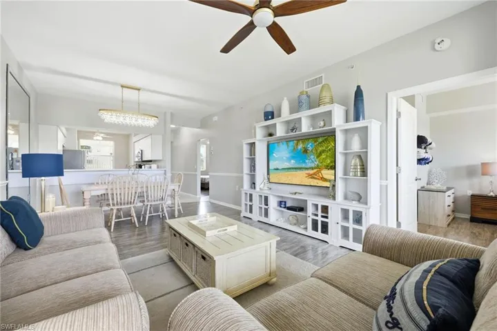 Open-concept living area featuring wood-finish flooring, a contemporary ceiling fan, and a built-in entertainment center with integrated shelving