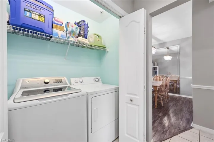 Dedicated laundry closet featuring a washer and dryer, an overhead wire shelf, and a light blue wall finish