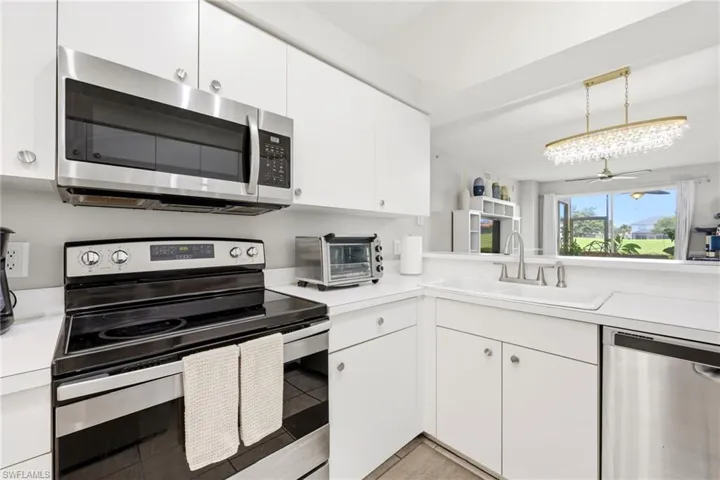 Well-appointed kitchen featuring white cabinetry, stainless steel appliances, a built-in microwave, and a white sink with a brushed nickel faucet
