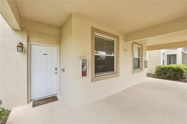 Entryway featuring a white paneled door, exterior wall lantern, two windows with blinds, and a built-in fire extinguisher cabinet