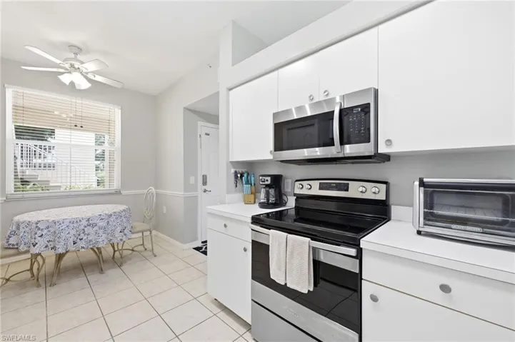 Kitchen featuring white cabinetry, stainless steel appliances, a white countertop, and tile flooring