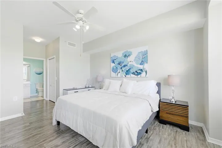 Spacious bedroom featuring wood-finish flooring, a ceiling fan with integrated lighting, and a neutral wall palette
