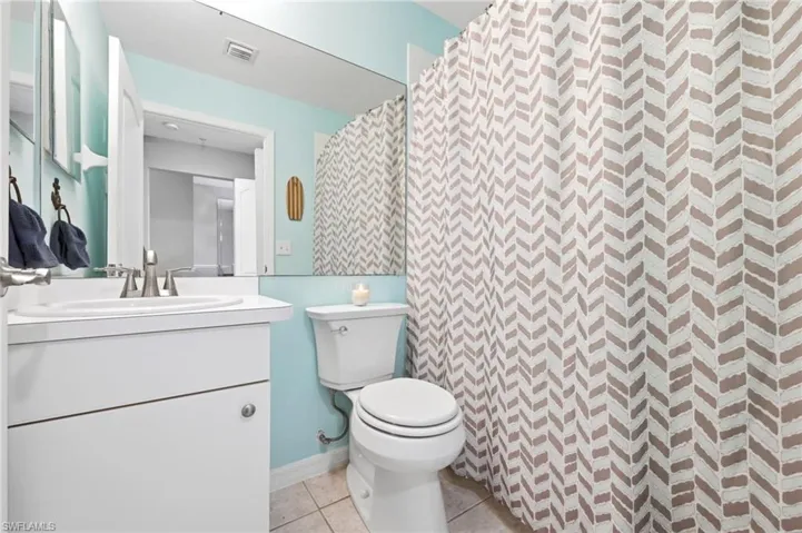 Bathroom featuring a white vanity with integrated sink, brushed nickel faucet, full-width wall mirror, and light blue wall color