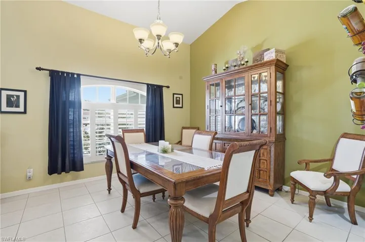 Dining area with a chandelier, light tile patterned floors, and vaulted ceiling