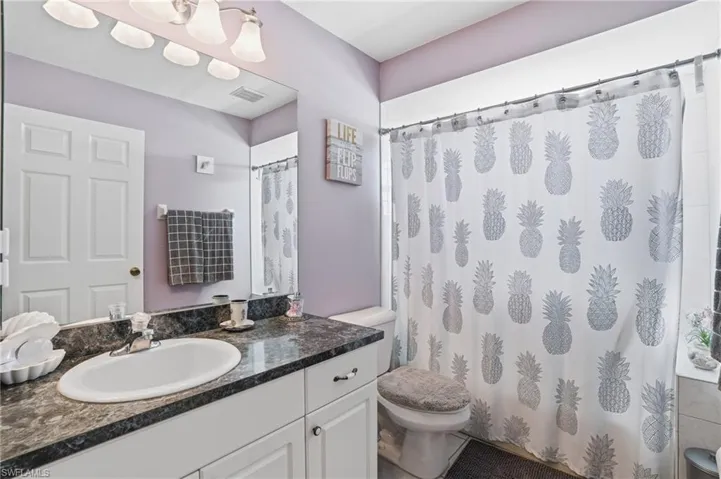 Full bathroom with curtained shower and vanity