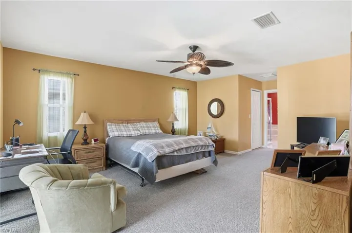 Carpeted bedroom featuring ceiling fan and a closet
