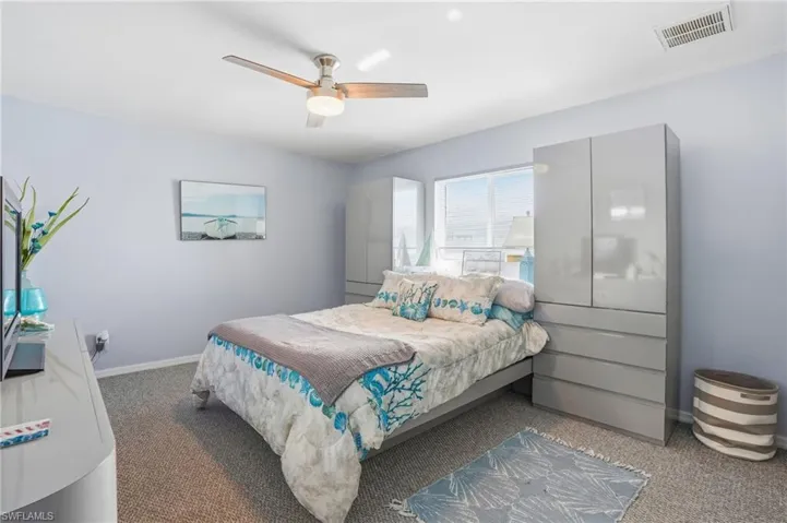 Carpeted bedroom featuring ceiling fan and baseboards