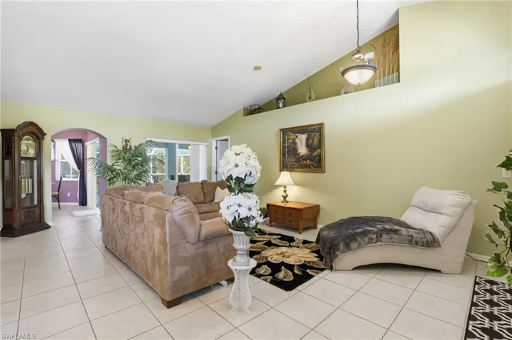 Living area with lofted ceiling, tile patterned floors, and arched walkways