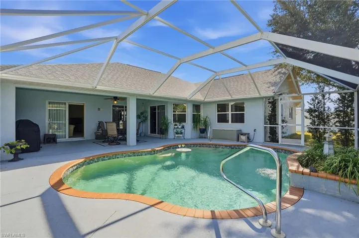 Outdoor pool featuring a lanai, a patio area, a sunroom, and area for grilling