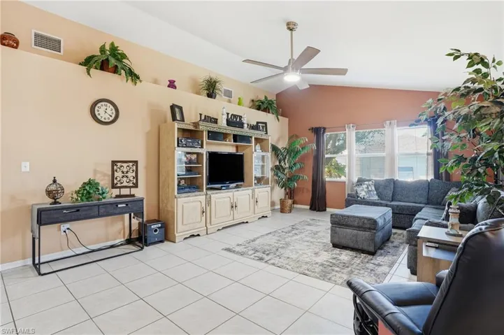 Living area with lofted ceiling, a ceiling fan, and light tile patterned floors