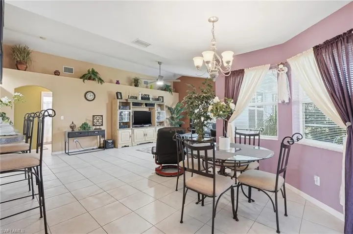Dining room with light tile patterned floors, ceiling fan, healthy amount of natural light, and a chandelier