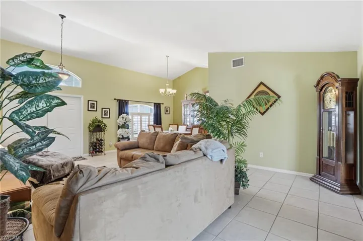 Living room featuring light tile patterned floors, a chandelier, and high vaulted ceiling