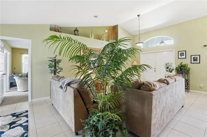 Living room featuring light tile patterned floors, plenty of natural light, and high vaulted ceiling