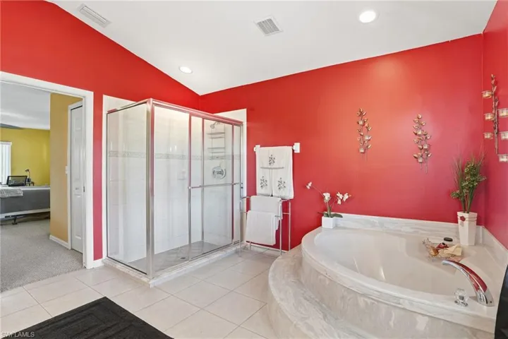 Ensuite bathroom featuring a bath, a stall shower, tile patterned flooring, recessed lighting, and vaulted ceiling