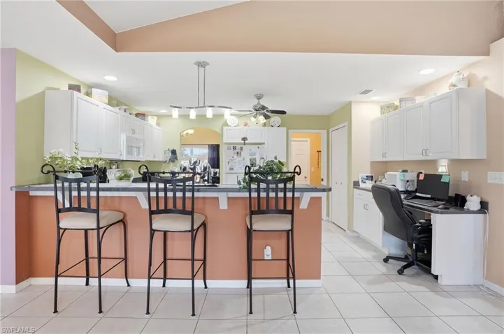Kitchen with white cabinets, recessed lighting, a peninsula, a breakfast bar, and white appliances