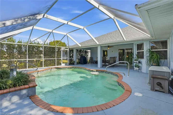 Swimming pool featuring glass enclosure, a sunroom, a patio, and a grill