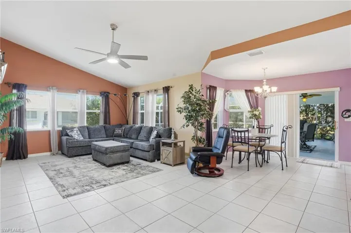 Living area featuring ceiling fan, vaulted ceiling, a chandelier, light tile patterned flooring, and healthy amount of natural light