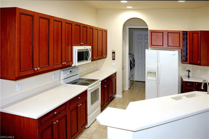 Kitchen wood cabinetry, light appliances and counter tops, and light tile flooring