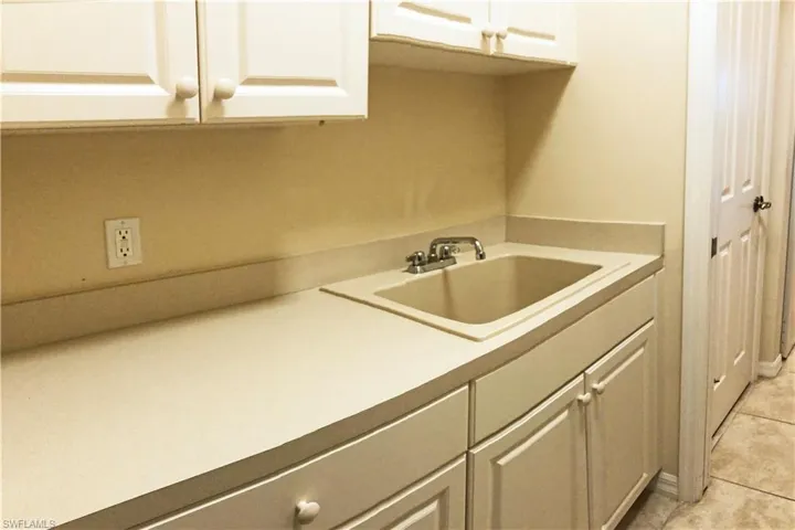 Laundry room with white cabinets, a sink and counter work area