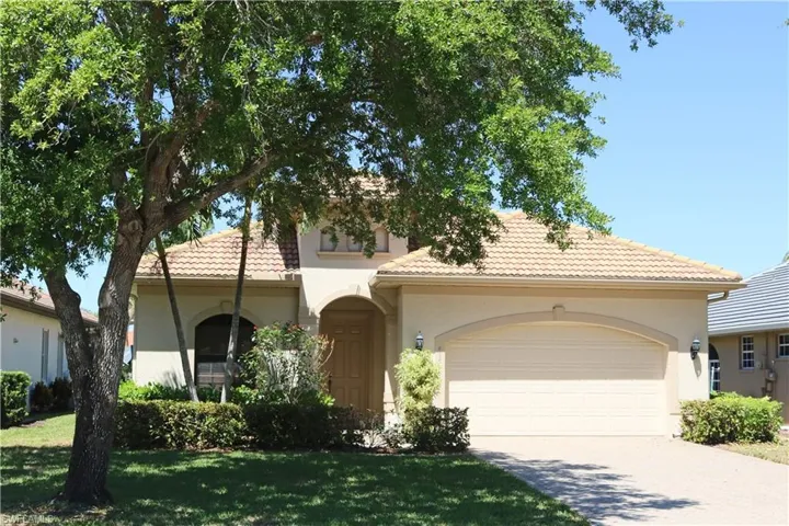 Mediterranean-style house with paver riveway,2-car garage, and tiled roof