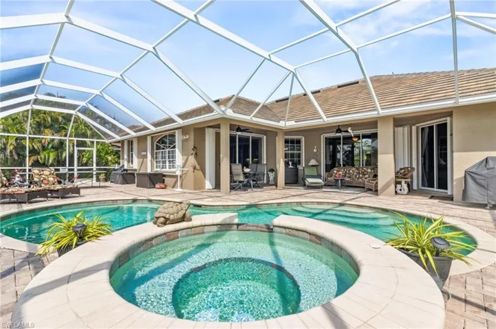 View of swimming pool featuring ceiling fan, a patio area, glass enclosure, and an in ground hot tub