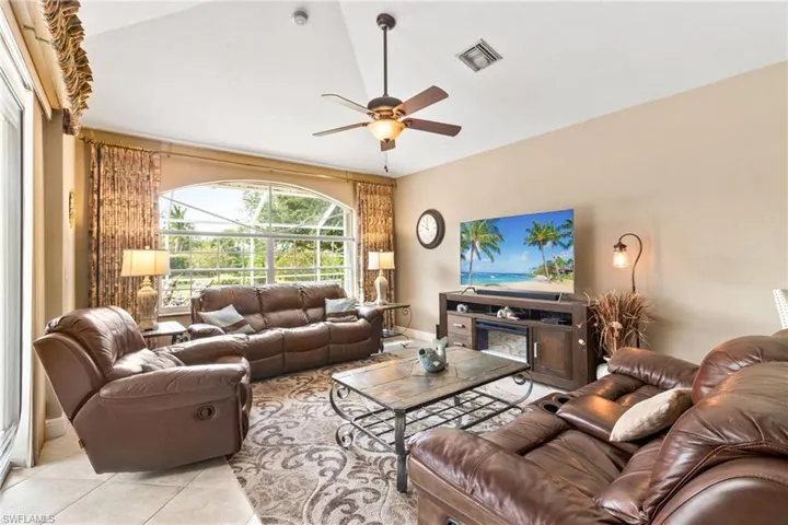 Tiled living room with ceiling fan and lofted ceiling