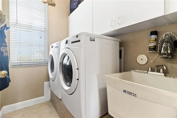 Washroom with washer and dryer, cabinets, sink, and light tile flooring