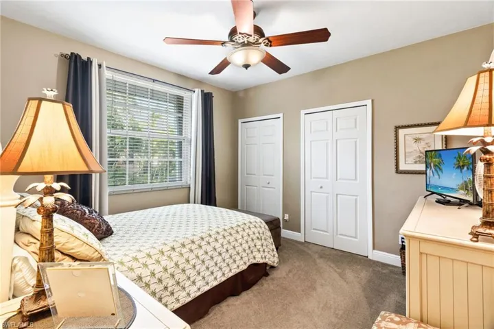 Carpeted bedroom featuring multiple closets and ceiling fan