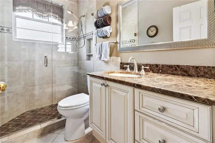 Bathroom with tile floors, walk in shower, vanity, and toilet
