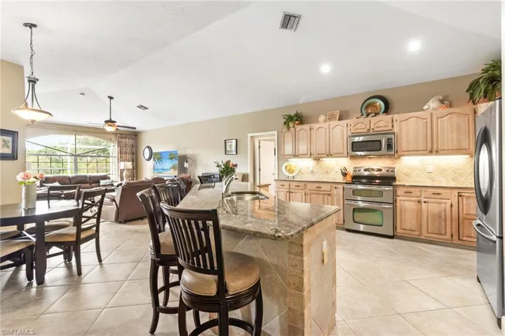 Kitchen featuring ceiling fan, an island with sink, stainless steel appliances, sink, and stone countertops