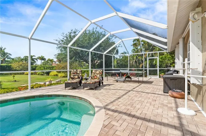 View of swimming pool with a patio, glass enclosure, and a yard