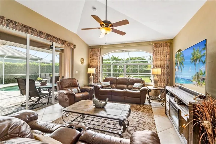 Living room featuring vaulted ceiling, ceiling fan, and light tile flooring