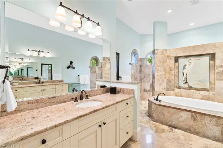 Bathroom with vanity, a garden tub, walk in shower, and light marble finish flooring