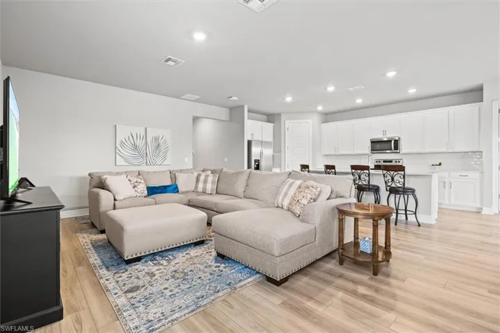 Living room with light vinyl plank floors and recessed lighting