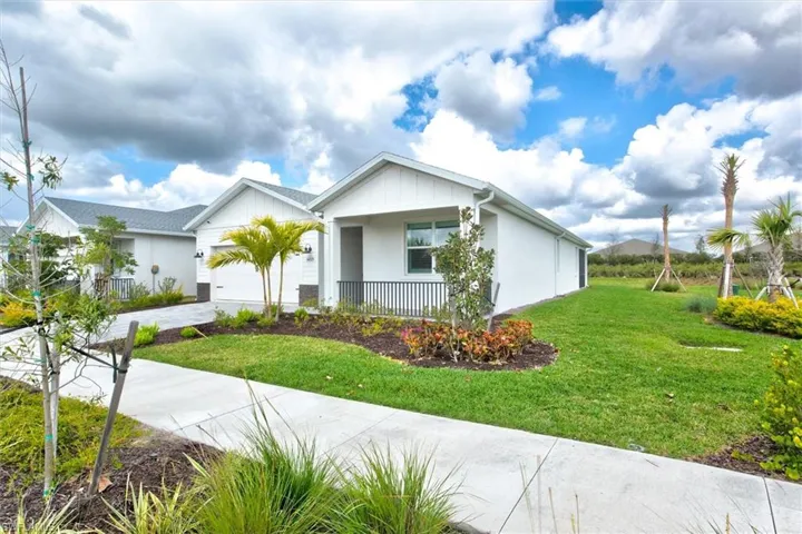 View of front of house featuring a front lawn, covered porch, concrete driveway, and an attached garage
