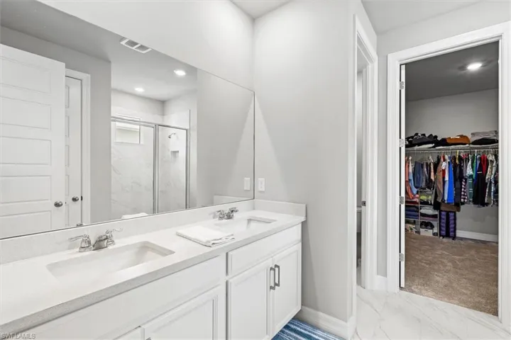 Full bathroom with tile floors, a spacious closet, double vanity, and recessed lighting
