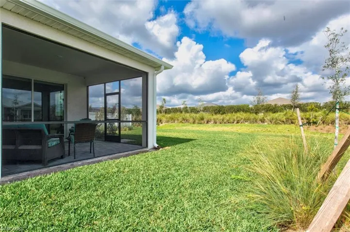 View of grassy yard featuring a sunroom