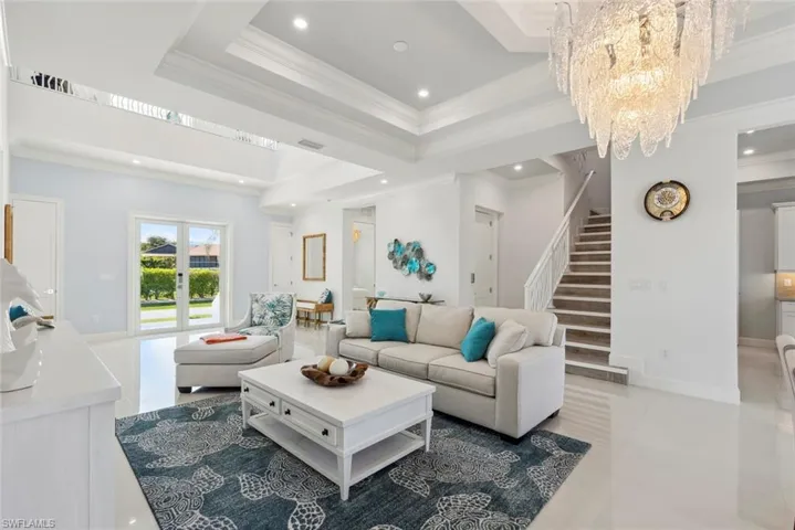 Living area featuring crown molding, stairway, recessed lighting, an inviting chandelier, and a raised ceiling