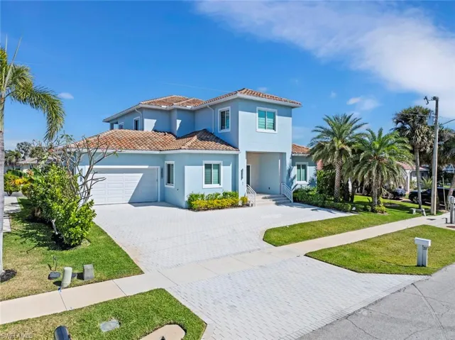 Mediterranean / spanish home featuring driveway, an attached garage, stucco siding, a front lawn, and a tile roof