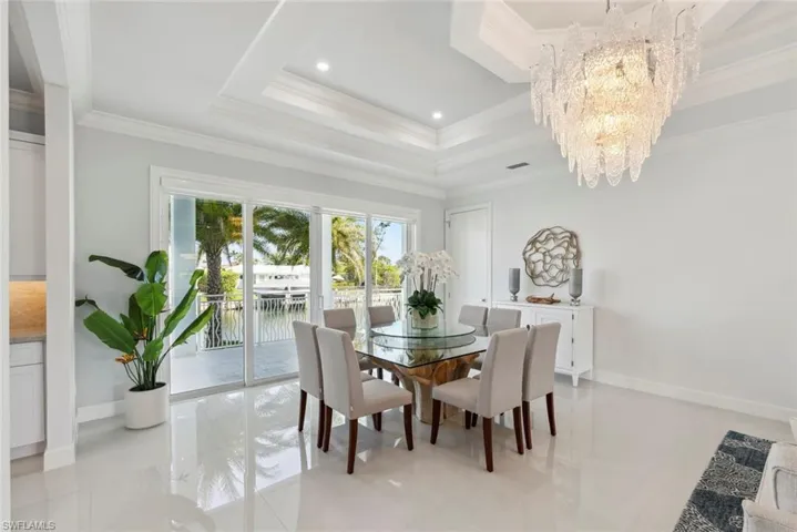 Dining area featuring crown molding, baseboards, recessed lighting, a notable chandelier, and a raised ceiling