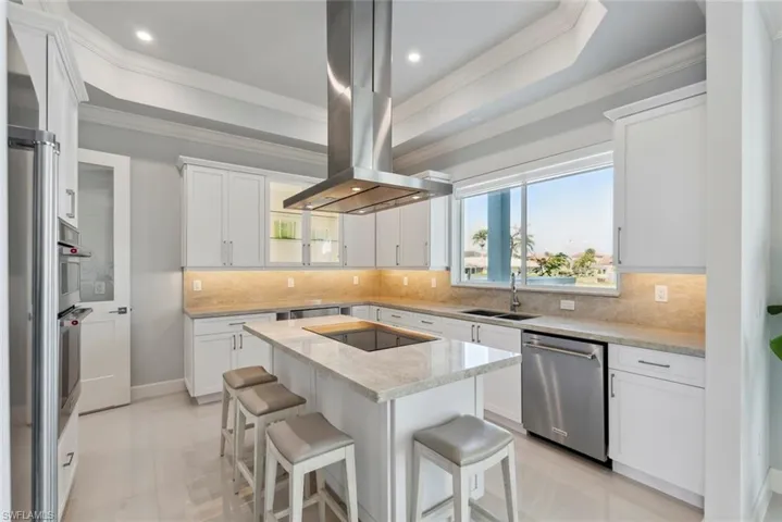 Kitchen featuring a sink, a kitchen island, island range hood, black electric cooktop, and dishwasher