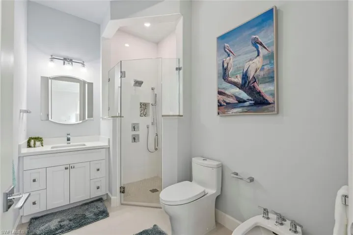 Bathroom with vanity, a bidet, baseboards, a stall shower, and toilet
