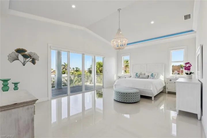 Bedroom with visible vents, a notable chandelier, light tile patterned floors, lofted ceiling, and access to exterior