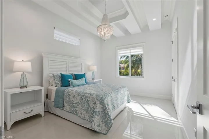 Bedroom featuring baseboards, recessed lighting, ornamental molding, a raised ceiling, and a notable chandelier