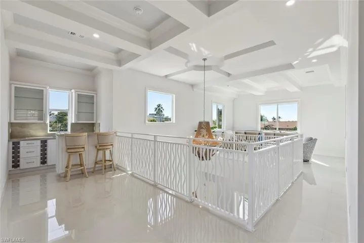 Living area with visible vents, ceiling fan, baseboards, ornamental molding, and beam ceiling