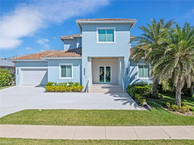 View of front of property featuring stucco siding, driveway, a tile roof, french doors, and a garage