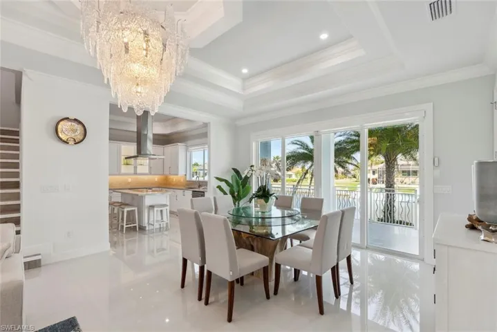 Dining area featuring stairs, an inviting chandelier, visible vents, and a raised ceiling
