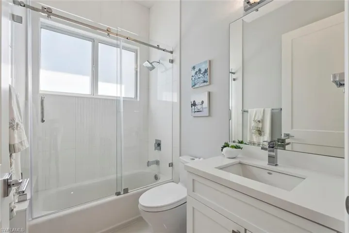 Full bathroom featuring combined bath / shower with glass door, toilet, and vanity