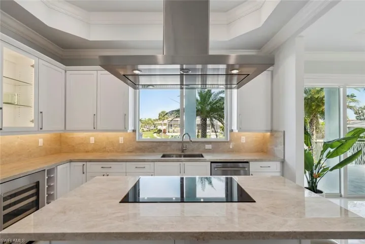 Kitchen with a sink, wine cooler, island range hood, crown molding, and black electric cooktop