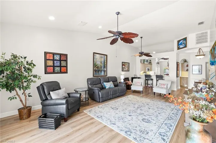 Living room featuring ceiling fan, vaulted ceiling, light wood finished floors, and recessed lighting